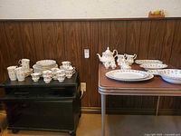 Overview of dinnerware on two tables showing plates, cups, saucers and serve pieces