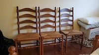 Three ladder-back chairs side by side showing overall style and condition