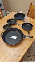 Five cast iron skillets of varying sizes on table