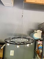 Large circular chandelier hanging, showing 8 glass votive cups and suspension cables