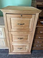 Front view of wooden file cabinet showing three drawers and key lock