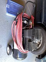 Side view of wheeled air compressor with red hose and blue bin