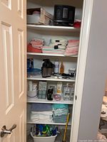 Full view of closet shelves with towels, heater, vaporizer, hand sanitizer, tissues and personal care items