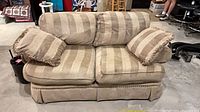 Front view of beige striped loveseat with two pillows