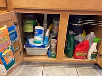 Overall view of cabinet interior with assorted cleaning bottles and supplies