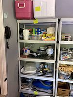 Full shelf view with coolers on top, pitcher, kitchen wraps, waffle maker, vacuum, storage containers visible