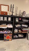 Overall lot on two black shelves with frames, games, bins, boxes