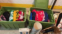 Two totes filled with jerseys, trophies, decorative container visible