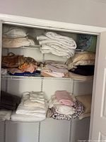 Closet view showing multiple shelves of assorted folded linens