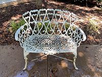 Front view of ornate cast metal outdoor bench on patio