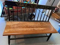 Front view showing entire wooden bench with spindle back and floral crest rail