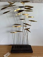 Full view of sculpture showing brass fish, rods, base, size perspective