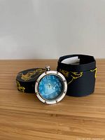 Front view of nickel Eye of Time clock and box lid