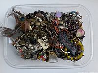 Top view of plastic bin filled with mixed costume jewelry
