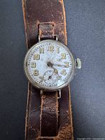 Front view of trench watch on strap, showing entire watch and leather band