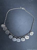 Full view of necklace showing eight spiral discs, chain and clasp