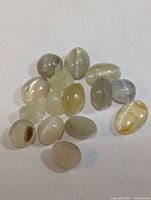 Group of small oval cat's eye cabochon gemstones on white background