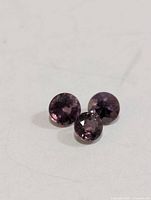 Three round faceted gemstones on neutral background