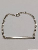 Full view of silver curb-link bracelet with ID bar and clasp