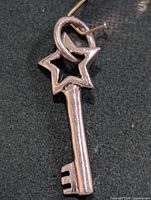 Front view of silver key pendant showing star bow and bail
