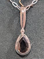 Close-up of sterling silver necklace showing pear-shaped smokey quartz pendant and part of chain