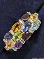 Front angled view of silver ring displaying multicolored gemstones