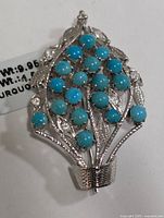 Front view of silver brooch with turquoise cabochons