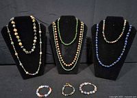 Group shot of all necklaces displayed on three forms with four bracelets below