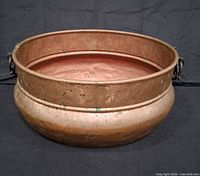 Side view of copper cauldron showing body shape and brass handle