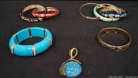 overview of bracelets and pendant on black background