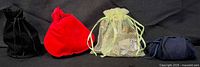 Four drawstring pouches: black velvet, red velvet, light green organza filled with jewelry, navy velvet