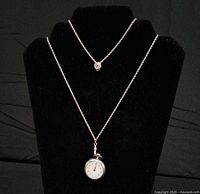 Both necklaces displayed; pocket watch and stone pendant visible