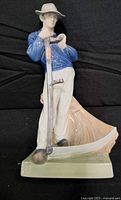 Front view of figurine showing farmer with scythe, colours and stance
