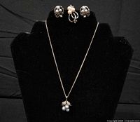 Full view of necklace on display bust with earrings and ring above