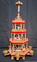 Full view of four-tier wooden Christmas pyramid showing candle cups and spindle top
