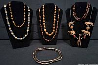 Three display stands with five wooden bead necklaces and one additional necklace laid flat