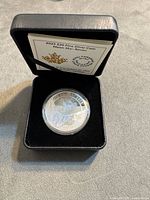 Coin in clear capsule inside black clamshell presentation case with insert card