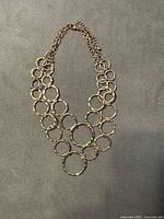 Full view of gold-tone hammered circle link necklace on flat surface
