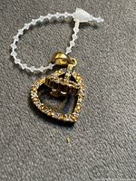 Front view of gold-tone heart brooch/pendant showing rhinestone detailing