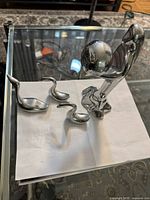 Group shot of all four polished aluminum sculptures on glass table
