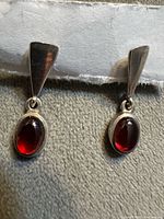 Front view of both earrings on backing card showing drop shape and red stones