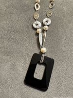 Close-up of decorative section showing pearls, white rings, silver links and pendant connection