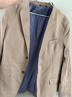 Front view of khaki Banana Republic sport coat on hanger, interior blue gingham lining visible