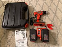 Complete set on floor: drill, two batteries, charger, case, manual