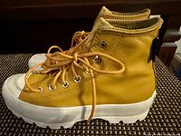 Left side view of both high-top sneakers showing yellow leather uppers, lugged sole, laces, eyelets