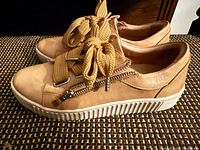 Side view of both sneakers showing leather upper, side zipper and rubber sole