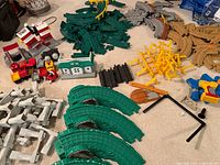 Overview of assorted GeoTrax tracks, risers, vehicles, building, controllers and accessories spread on carpet