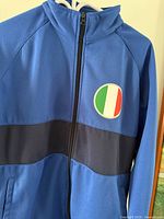 Front of blue Italy Euro 2020 jacket with flag crest and black stripe