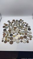 Overview of roughly 100 assorted UK coins laid out on white background