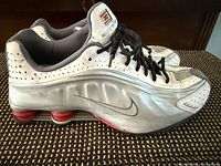 Side profile of both shoes showing Nike swoosh, red Shox columns, overall condition